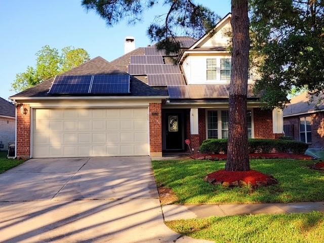 18534 Wolf Creek Trl, Humble, TX 77346 - view of front of house featuring brick siding, driveway, a garage, and solar panels