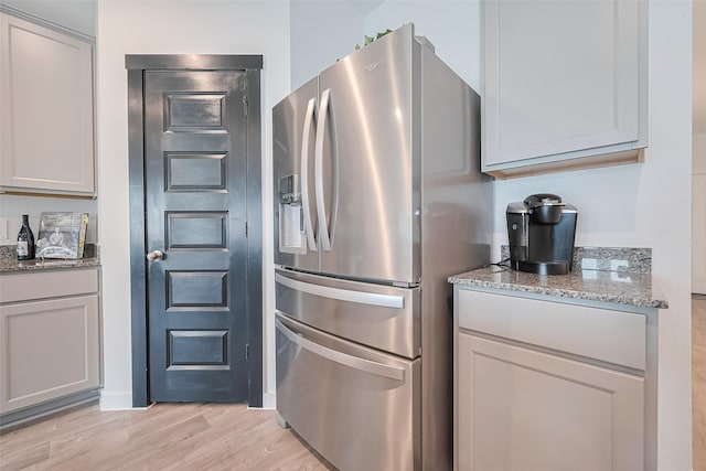 31707 Whittis Hill Way, Fulshear, TX 77441 - kitchen featuring stainless steel refrigerator with ice dispenser, light stone counters, and light wood-type flooring