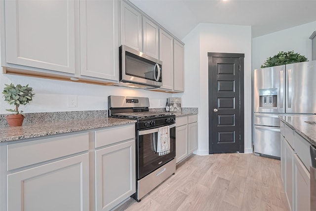 31707 Whittis Hill Way, Fulshear, TX 77441 - kitchen with appliances with stainless steel finishes, light stone counters, and light wood-type flooring