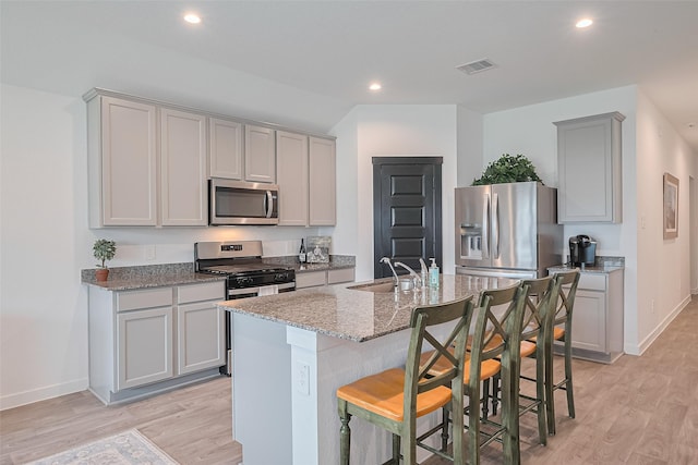 31707 Whittis Hill Way, Fulshear, TX 77441 - kitchen featuring appliances with stainless steel finishes, a sink, light wood-type flooring, gray cabinets, and light stone counters