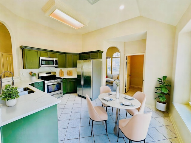 4142 Surreydon Dr, Houston, TX 77014 - kitchen featuring green cabinets, stainless steel appliances, arched walkways, a sink, and light tile patterned flooring