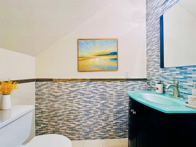 4142 Surreydon Dr, Houston, TX 77014 - half bath featuring tile walls, vaulted ceiling, toilet, tile patterned floors, and wainscoting