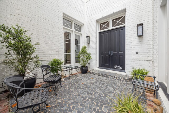 view of exterior entry featuring brick siding and covered porch