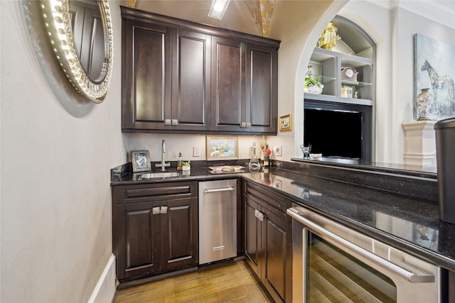 indoor wet bar with wine cooler, light wood-type flooring, built in features, and arched walkways