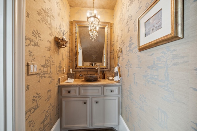 bathroom featuring wallpapered walls, vanity, and a chandelier