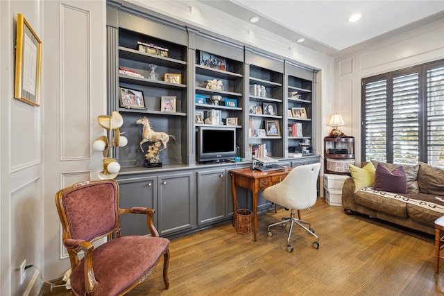 home office featuring light wood finished floors, a decorative wall, and recessed lighting