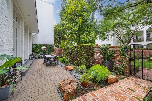 view of patio with outdoor dining area, a fenced backyard, and a gate