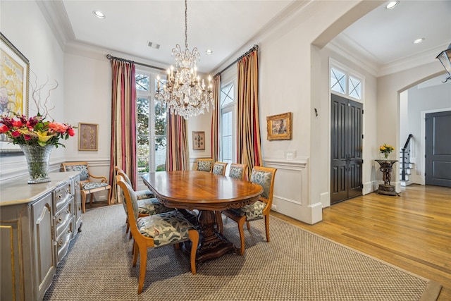 dining room with arched walkways, crown molding, light wood-type flooring, a chandelier, and recessed lighting