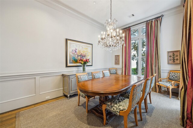 dining room with ornamental molding, a chandelier, a decorative wall, and wainscoting