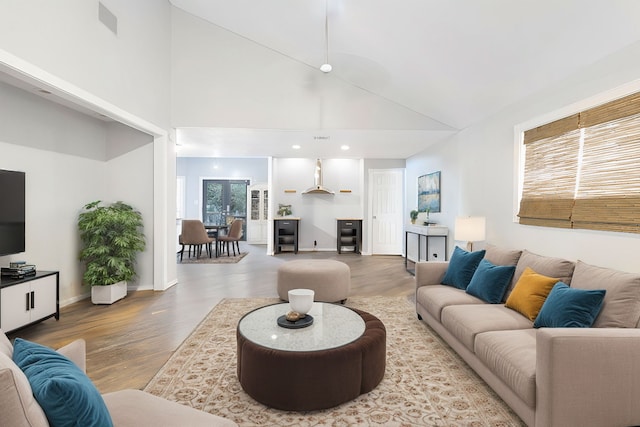 living room featuring wood finished floors, high vaulted ceiling, and baseboards