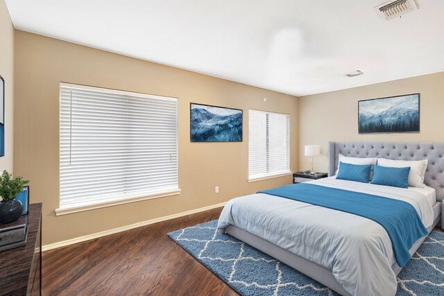 bedroom with wood finished floors, baseboards, and multiple windows