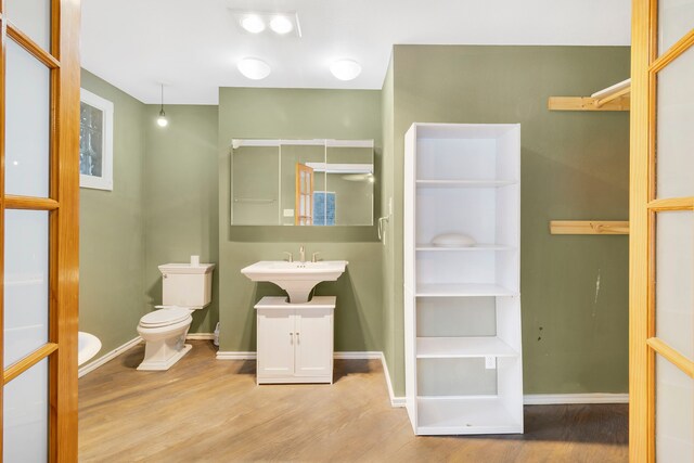 bathroom with wood finished floors, toilet, and baseboards