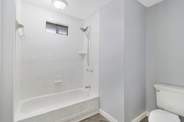 bathroom with toilet, shower / bathtub combination, and baseboards