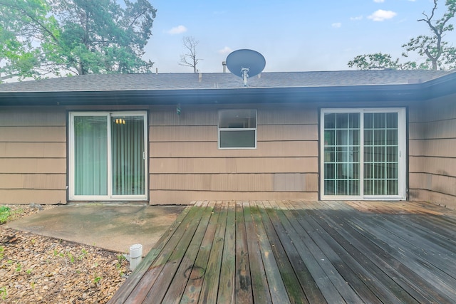 rear view of house with roof with shingles, a wooden deck, and a patio area