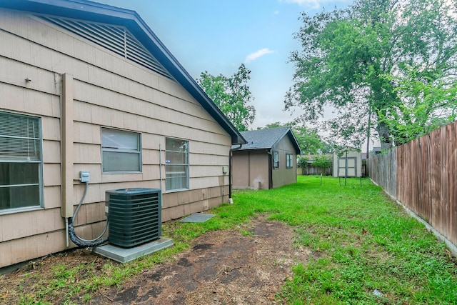view of yard with central AC unit, a storage unit, and an outbuilding