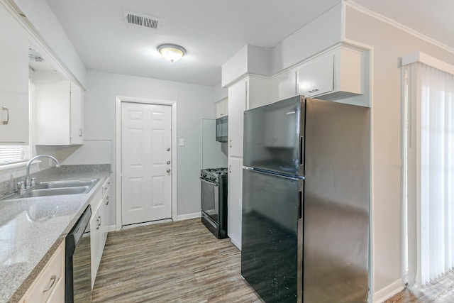 kitchen featuring black appliances, a sink, white cabinetry, light wood-style flooring, and light countertops