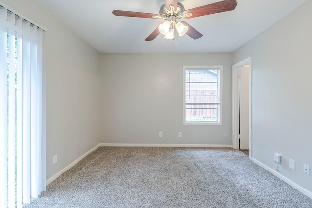 carpeted spare room featuring plenty of natural light, ceiling fan, and baseboards