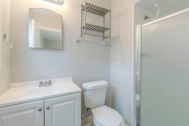 bathroom featuring toilet, a stall shower, and vanity