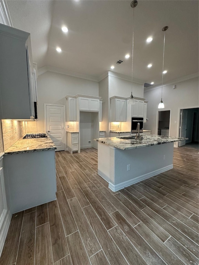 kitchen with ornamental molding, light stone countertops, dark wood finished floors, white cabinetry, and stainless steel appliances
