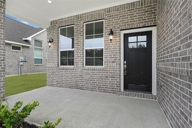 310 Little Spring Ct, Anahuac, TX 77514 - view of exterior entry with brick siding and a patio area