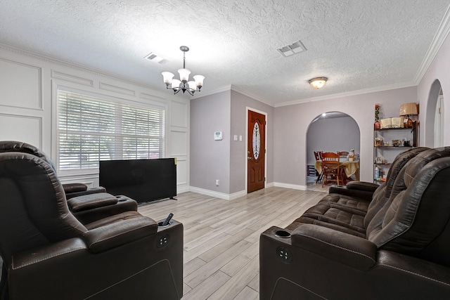living room featuring a chandelier, light wood-style flooring, arched walkways, ornamental molding, and a textured ceiling