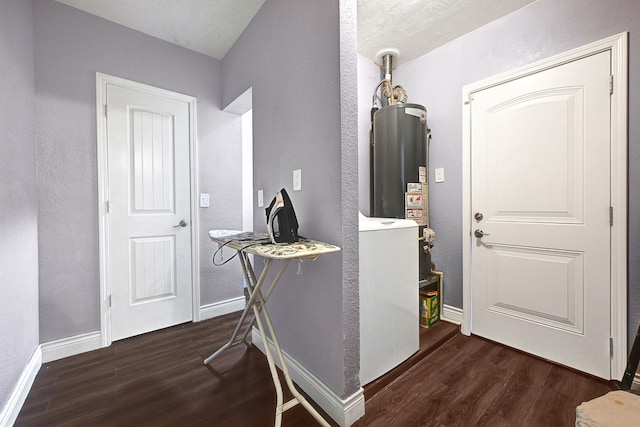 foyer entrance with wood finished floors, baseboards, a textured wall, and water heater
