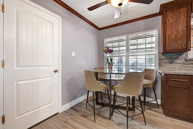 dining area with ornamental molding, ceiling fan, light wood-style floors, and baseboards