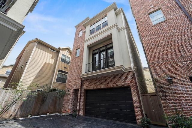 rear view of property with an attached garage, fence, french doors, and brick siding