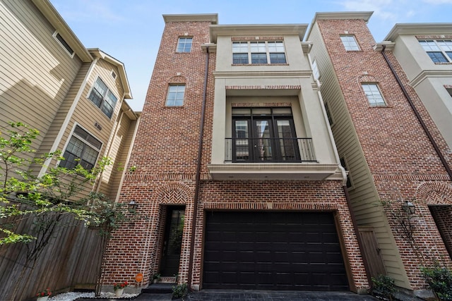 rear view of property featuring an attached garage, brick siding, fence, and a balcony