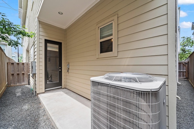 view of exterior entry with central air condition unit, fence, and a patio