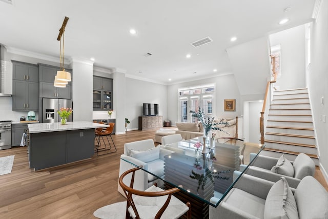 dining room with light wood-style flooring, recessed lighting, stairs, crown molding, and baseboards