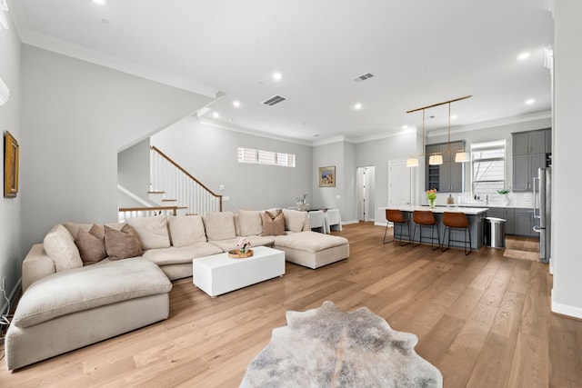 living area with recessed lighting, light wood-style flooring, crown molding, and baseboards