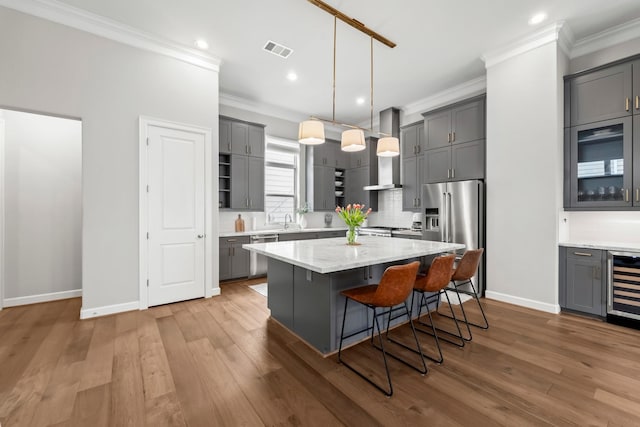 kitchen featuring appliances with stainless steel finishes, crown molding, gray cabinets, beverage cooler, and baseboards