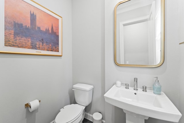 bathroom featuring toilet, a sink, and baseboards