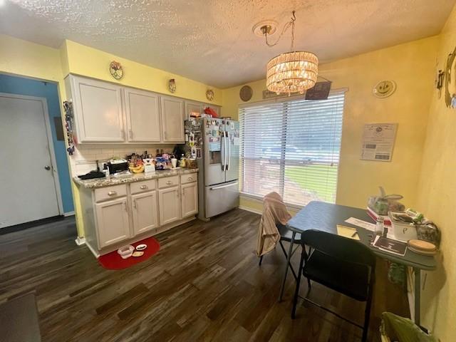 kitchen featuring stainless steel fridge with ice dispenser, dark wood-type flooring, a chandelier, light countertops, and a textured ceiling