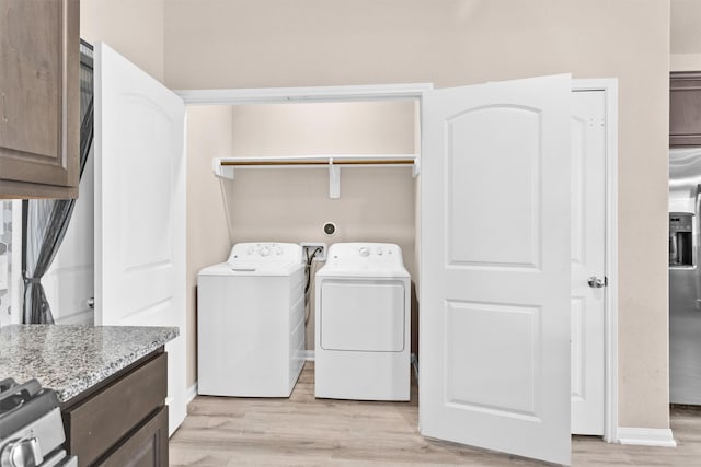 14108 Kamilia Rd, Conroe, TX 77306 - clothes washing area featuring light wood-style floors, washing machine and clothes dryer, and baseboards
