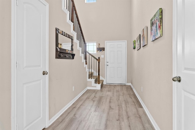 14108 Kamilia Rd, Conroe, TX 77306 - corridor featuring light wood finished floors, baseboards, stairway, and a towering ceiling