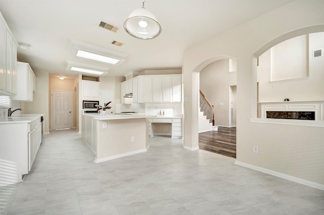 8215 Still Oak Ln, Cypress, TX 77433 - kitchen featuring stainless steel microwave, a center island with sink, light countertops, white cabinets, and a sink