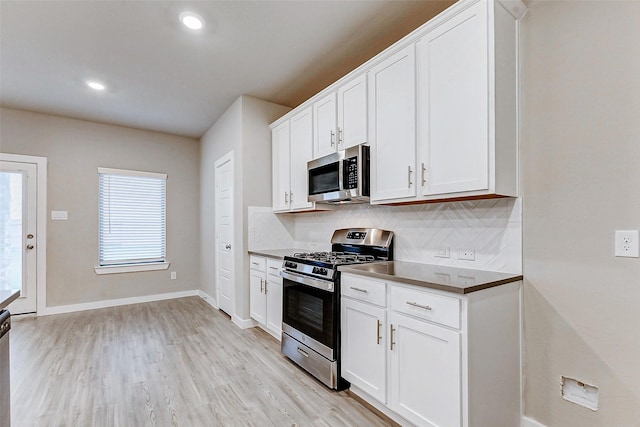 8119 Blue Fish Dr, Cypress, TX 77433 - kitchen with appliances with stainless steel finishes, decorative backsplash, light wood finished floors, white cabinetry, and recessed lighting