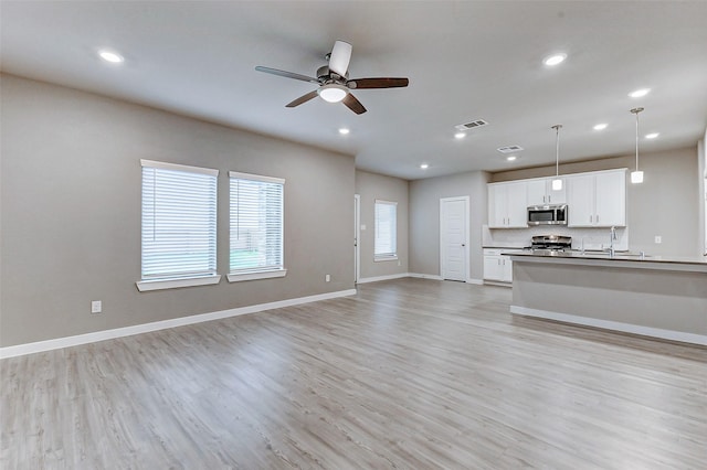 8119 Blue Fish Dr, Cypress, TX 77433 - unfurnished living room featuring ceiling fan, light wood finished floors, recessed lighting, baseboards, and a sink