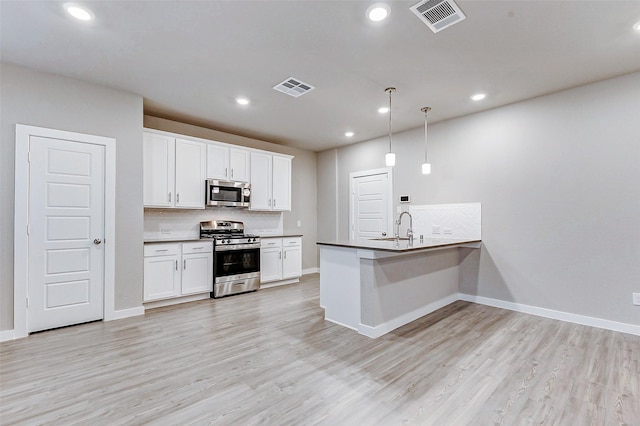 8119 Blue Fish Dr, Cypress, TX 77433 - kitchen with appliances with stainless steel finishes, a peninsula, backsplash, a sink, and white cabinetry