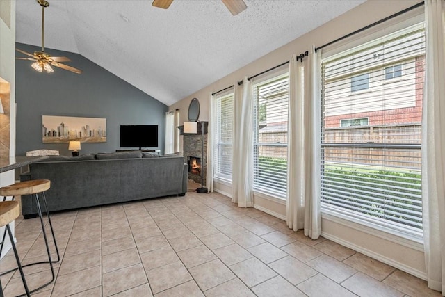 9302 Kirkchapel Ct, Spring, TX 77379 - living area featuring ceiling fan, a textured ceiling, a stone fireplace, light tile patterned floors, and lofted ceiling