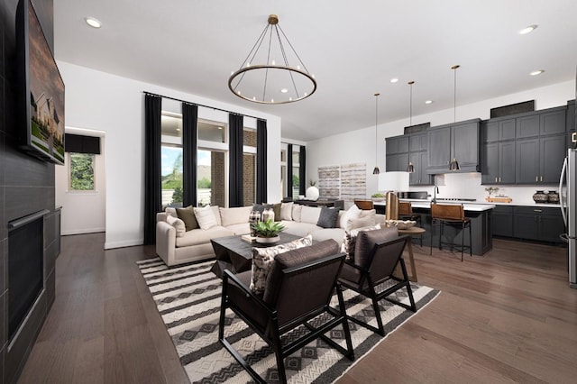 living area featuring dark wood finished floors, recessed lighting, a chandelier, a fireplace, and baseboards
