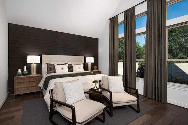 bedroom with wood finished floors, high vaulted ceiling, wooden walls, and baseboards