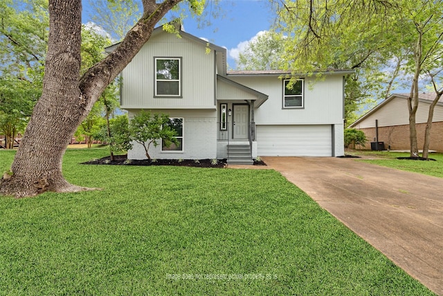 bi-level home with an attached garage, concrete driveway, brick siding, and a front yard