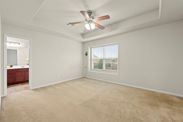 15010 Calico Heights Ln, Cypress, TX 77433 - unfurnished bedroom with light colored carpet, a tray ceiling, baseboards, ensuite bathroom, and ceiling fan