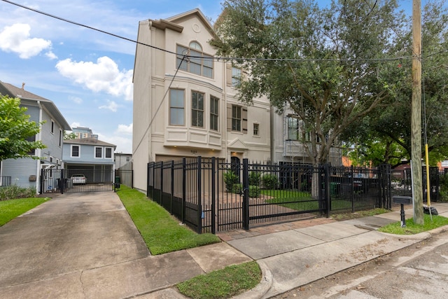 view of front of home with a gate, stucco siding, a fenced front yard, and concrete driveway