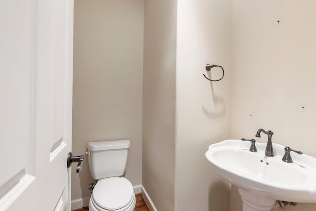 half bathroom with a sink, toilet, and baseboards