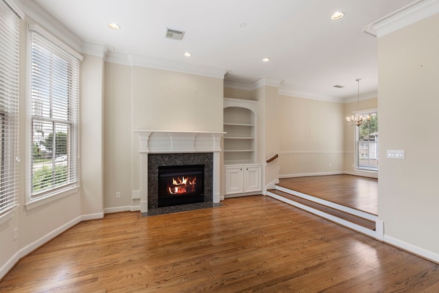 unfurnished living room with crown molding, wood finished floors, a fireplace, a chandelier, and recessed lighting