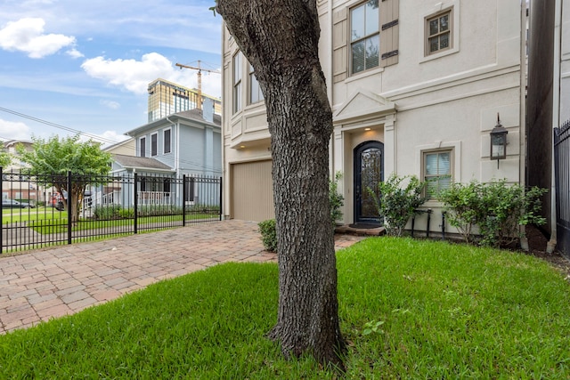 entrance to property with a garage, decorative driveway, and stucco siding